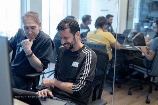 two coworkers sitting in front of a computer talking